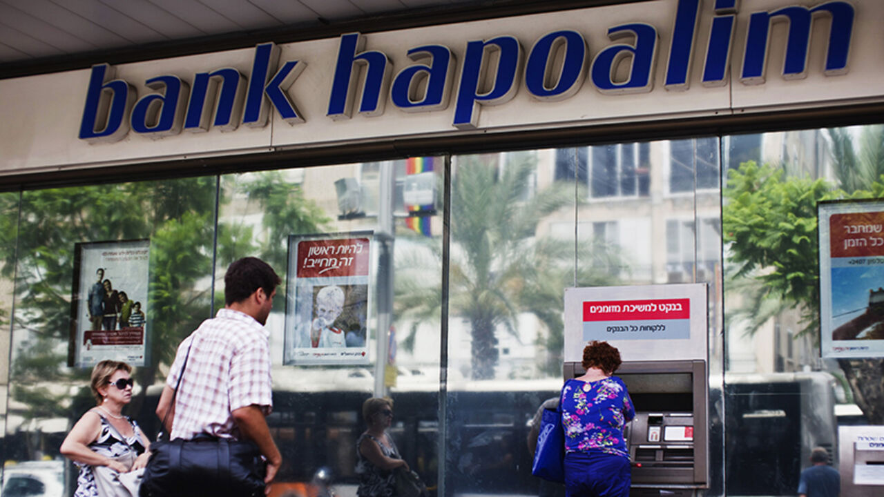 HAPOALIM-RESULTS/ A woman uses an automated teller machine (ATM) outside a Bank Hapoalim branch in Tel Aviv May 30, 2013. Tough economic conditions and low interest rates hurt first-quarter profits at Israel's top two banks Hapoalim and Leumi, and two surprise rate cuts in May are expected to have a further impact in the coming quarters. REUTERS/Nir Elias (ISRAEL - Tags: BUSINESS) - RTX1061J