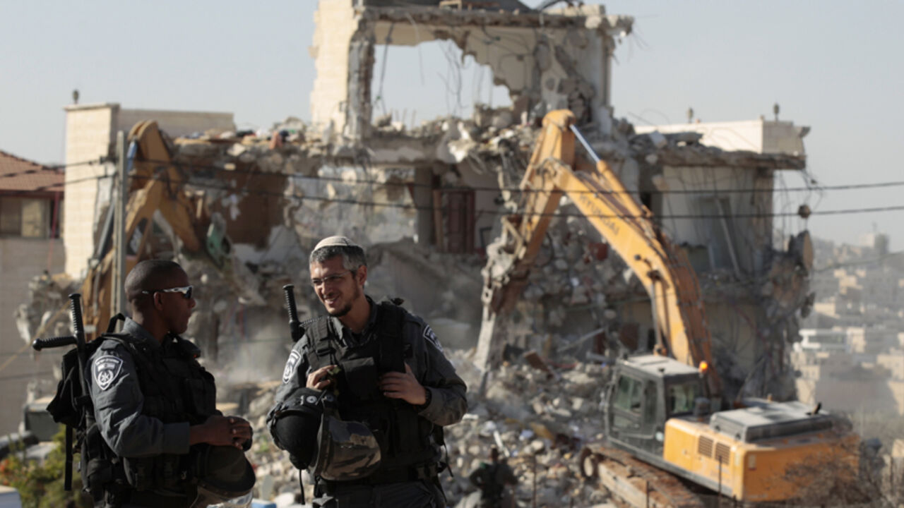 Israeli police officers stand guard as a house belonging to Palestinians is being demolished in the East Jerusalem neighbourhood of Beit Hanina October 29, 2013. A statement from the Jerusalem Municipality said there was a court order for the demolition of the house, which was built without a permit. REUTERS/Ammar Awad (JERUSALEM - Tags: POLITICS BUSINESS CONSTRUCTION) - RTX14SGL