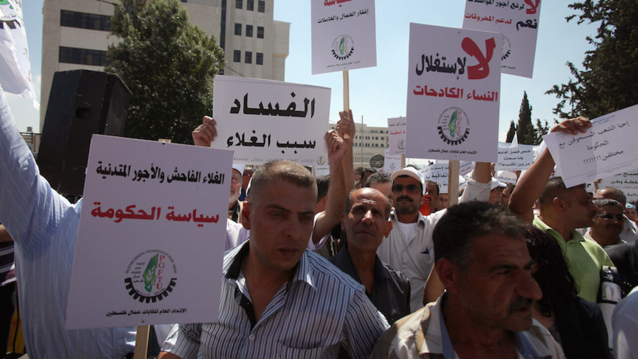 Nic6131583 Palestinian protesters hold signs that read in Arabic "Corruption is the reason for high cost of living" and "High prices and low wages are the policies of the government" during a protest against the high cost of living in the West Bank city of Ramallah on September 11, 2012. Palestinain prime minister Salam Fayyad announced cuts to fuel prices and VAT after more than a week of protests across the West Bank over the spiralling cost of living. AFP PHOTO/ABBAS MOMANI (Photo credit should read ABBAS MO