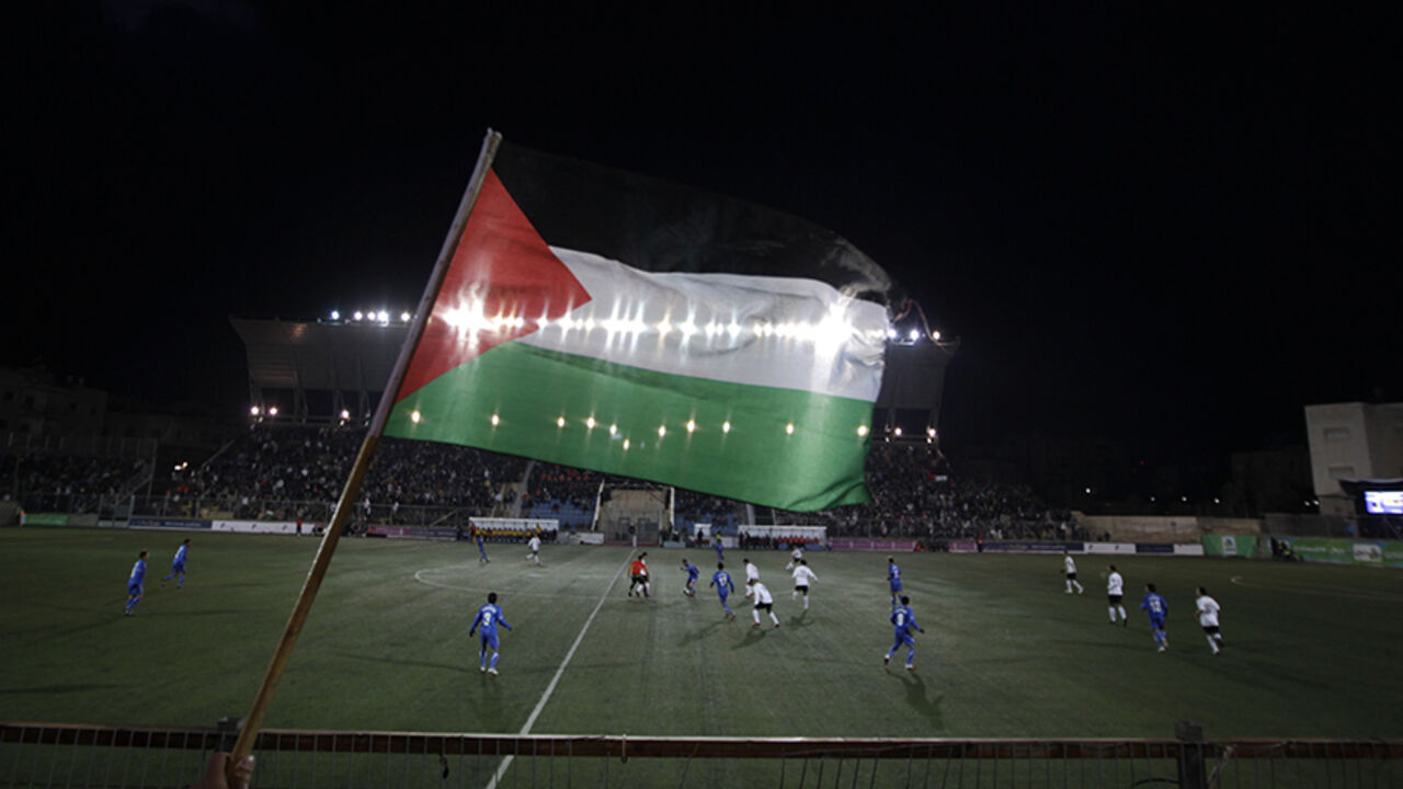 PALESTINIANS/ A Palestinian national flag is seen during the Olympic games qualifying match between Palestinian and Thai national soccer teams at a stadium in the West Bank town of A-Ram near Jerusalem March 9, 2011. The match is the first official international fixture to be hosted on Palestinian home soil. REUTERS/Ammar Awad (WEST BANK - Tags: SPORT SOCCER) - RTR2JOA8