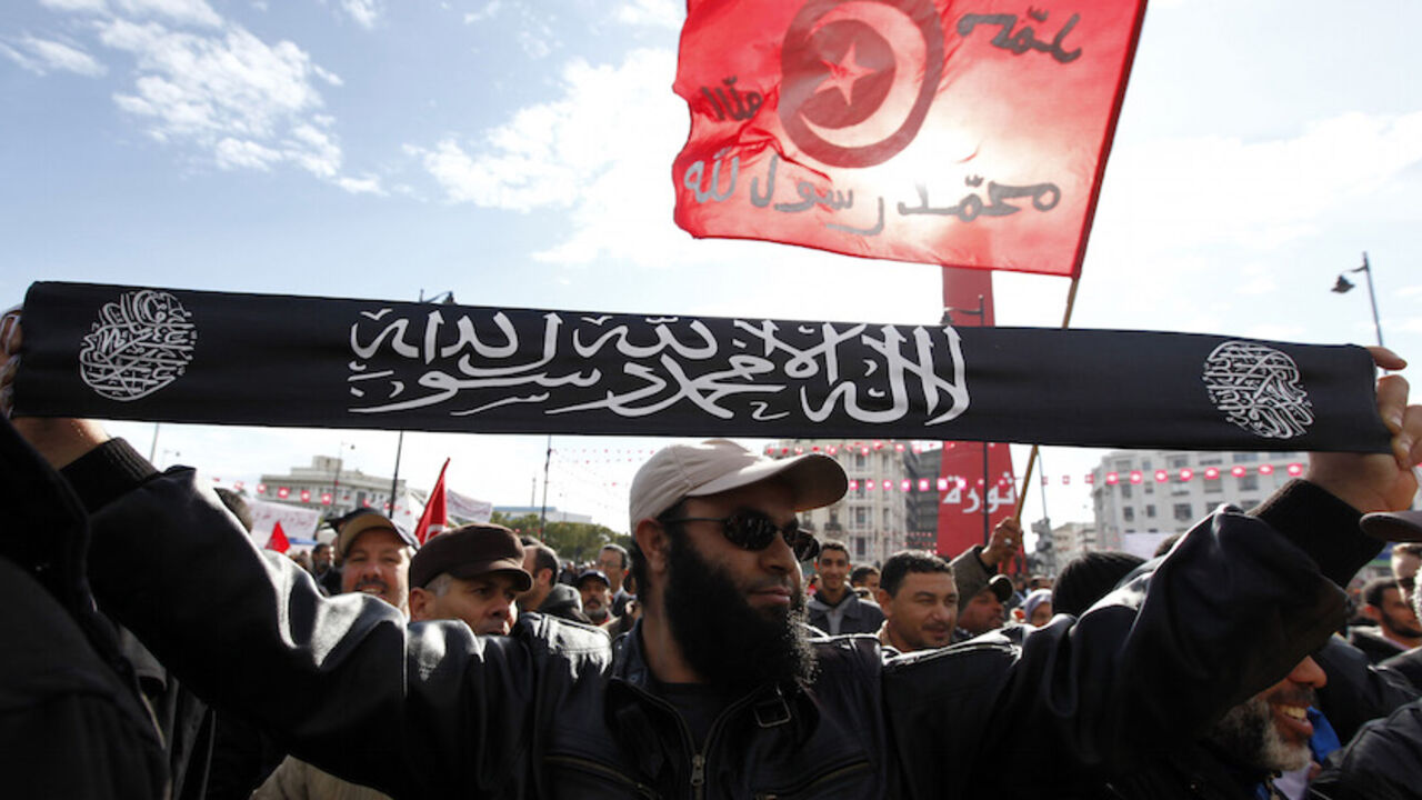 TUNISIA-PROTESTS/ A man from the Salafist faction holds up a banner that reads "There is no god but God, and Muhammad is the messenger of God", on the second anniversary of the Tunisian Revolution at Avenue Habib Bourguiba in Tunis January 14, 2013. Thousands of Tunisians protested against the Islamist-led government on Monday, exactly two years after the overthrow of President Zine El Abidine Ben Ali in a popular revolt that inspired others across the Arab world. In the same street, about 2,000 supporters of the Islamic-led