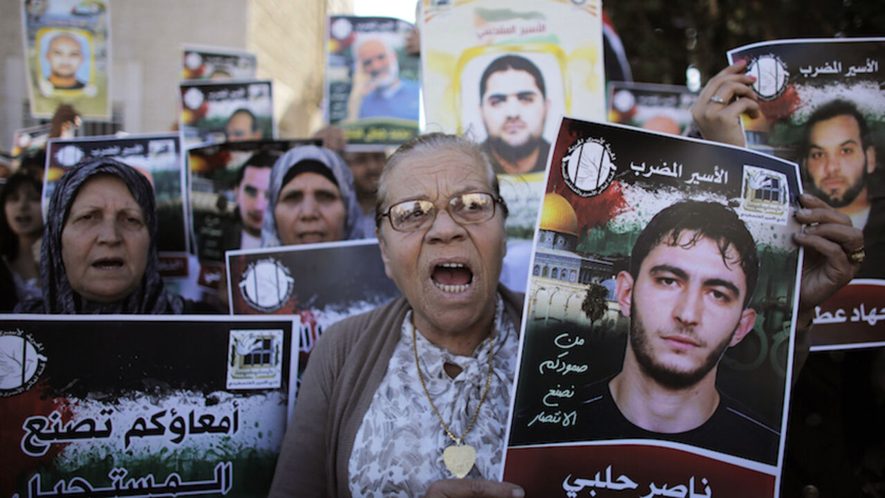 ISRAEL/ Palestinian protesters hold placards depicting their relatives during a demonstration to show their solidarity with hunger-striking Palestinian prisoners held by Israel, outside the Red Cross building in Jerusalem June 12, 2014. Some 70 protesters took part in the demonstration on Thursday. Hundreds of Palestinian prisoners in Israeli jails have joined a hunger strike since late April, in protest over an Israeli policy allowing indefinite detention without trial. REUTERS/Ammar Awad (JERUSALEM - Tags: POLITI