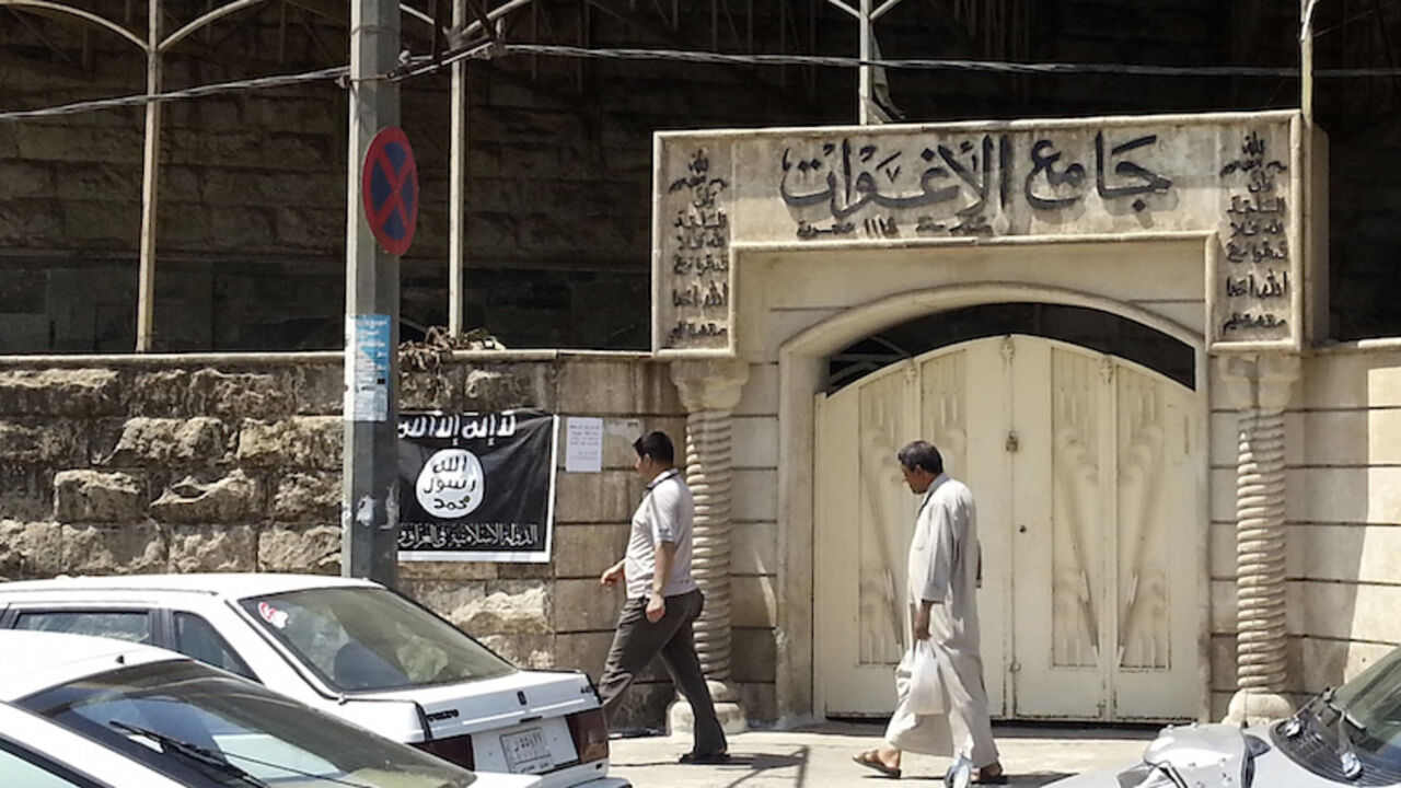IRAQ-SECURITY/ People walk past a banner (in black and white) belonging to the Islamic State in Iraq and the Levant (ISIL) in the city of Mosul, June 28, 2014. Since early June, ISIL militants have overrun most majority Sunni Muslim areas in the north and west of Iraq, capturing the biggest northern city Mosul and late dictator Saddam Hussein's hometown of Tikrit. The banner reads, "There is no God but God, and Mohammad is his messenger." REUTERS/Stringer (IRAQ - Tags: CIVIL UNREST POLITICS) - RTR3W71S