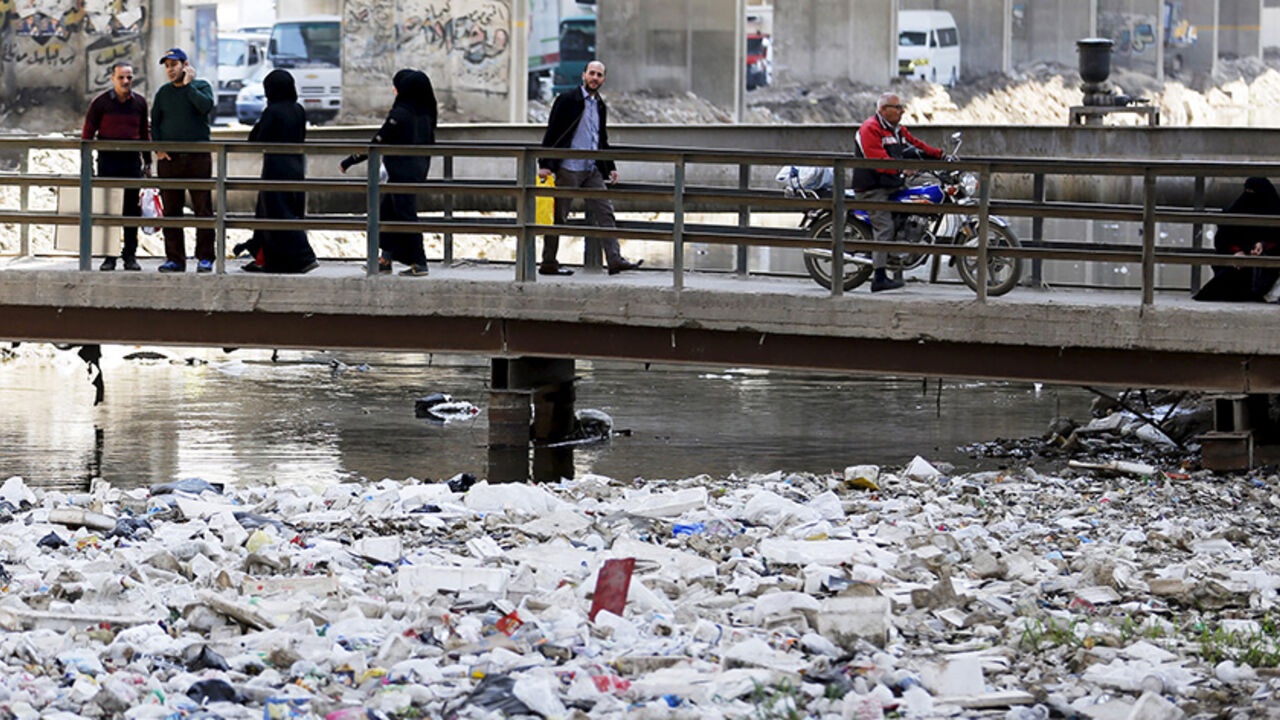 EGYPT-ENVIRONMENT/ People walk across a bridge surrounded by litter and waste at a canal connected to the river Nile in Cairo March 22, 2015. World Water Day is observed on March 22. REUTERS/Amr Abdallah Dalsh - RTR4UD5Y