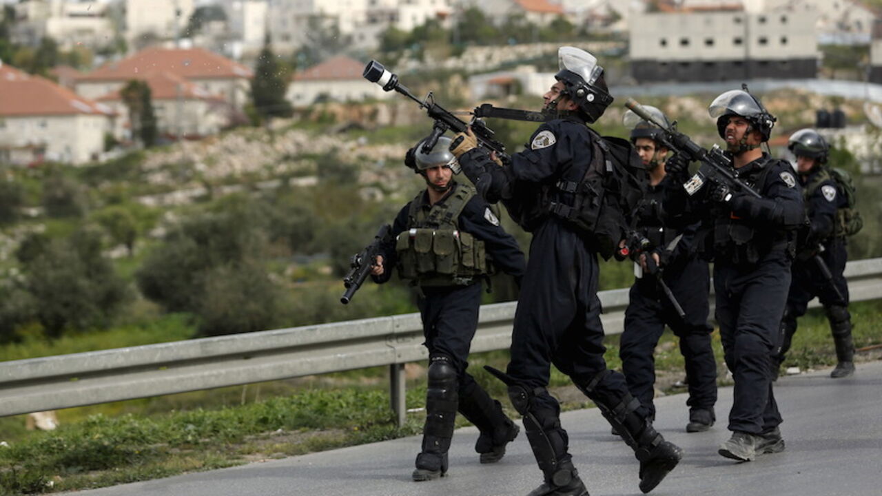 ISRAEL-PALESTINIANS/ An Israeli border policeman fires a tear gas canister towards Palestinian stone-throwers as an Israeli settlement is seen in the background during clashes at a protest against Jewish settlements, in Jalazoun refugee camp near the West Bank city of Ramallah March 27, 2015.
REUTERS/Mohamad Torokman - RTR4V6AH