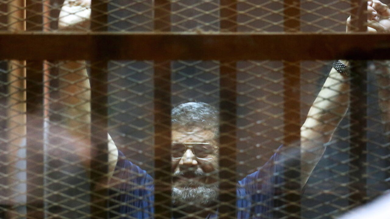 EGYPT-COURT/MURSI Former Egyptian President Mohamed Mursi waves during his trial at a court in the outskirts of Cairo, May 16, 2015. An Egyptian court on Saturday sought the death penalty for former president Mohamed Mursi and more than 100 other members of the Muslim Brotherhood in connection with a mass jail break in 2011. REUTERS/Mohamed Abd El Ghany - RTX1D7JE