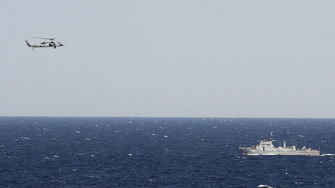 GULF-USA/ A helicopter from the Nimitz-class aircraft carrier USS Abraham Lincoln (CVN 72) hovers over an Iranian patrol ship during a transit through the Strait of Hormuz, February 14, 2012. REUTERS/Jumana El Heloueh (GULF - Tags: POLITICS MILITARY) - RTR2XU5R
