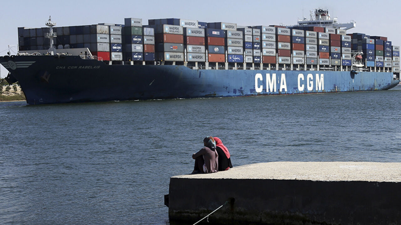 EGYPT-OIL/ Women sit and look at a container ship navigate through the Suez canal near Ismailia port city, northeast of Cairo May 2, 2014. Egypt has extended the bidding deadline to July 3 in an international auction of 22 concessions for oil and gas exploration, an official with the state-owned gas company said on Wednesday.The previous deadline for companies to submit bids for concessions in the Suez Canal, Egypt's western desert, the Mediterranean sea and the Nile Delta had been May 19. REUTERS/Amr Abdallah Dalsh