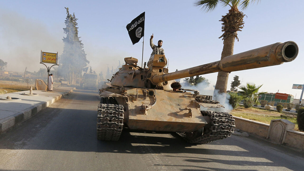 SYRIA-CRISIS/IRAQ Militant Islamist fighters on a tank take part in a military parade along the streets of northern Raqqa province June 30, 2014. Militant Islamist fighters held a parade in Syria's northern Raqqa province to celebrate their declaration of an Islamic "caliphate" after the group captured territory in neighbouring Iraq, a monitoring service said. The Islamic State, an al Qaeda offshoot previously known as Islamic State in Iraq and the Levant (ISIL), posted pictures online on Sunday of people waving black flags