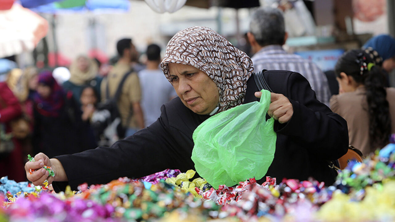 PALESTINIANS-RELIGION/ A Palestinian woman buys candies from a vendor at a market ahead of Eid al-Adha in the West Bank city of Nablus September 30, 2014. REUTERS/Abed Omar Qusini (WEST BANK - Tags: RELIGION SOCIETY) - RTR48DQO