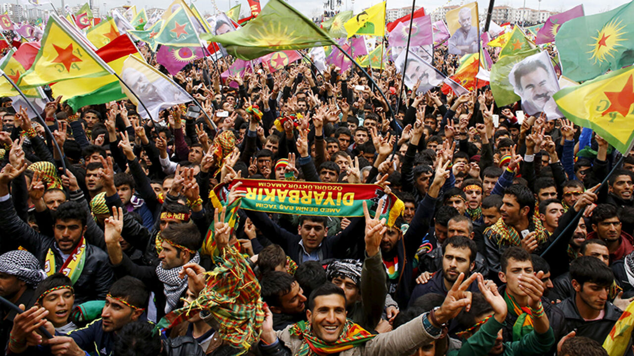 TURKEY-KURDS/ People gesture while others wave Kurdish flags during a gathering celebrating Newroz, which marks the arrival of spring and the new year, in Diyarbakir March 21, 2015. Jailed Kurdish rebel leader Abdullah Ocalan called on Saturday for his militant group to hold a congress on ending a three-decade insurgency against the Turkish state but stopped short of declaring an immediate halt to its armed struggle. Tens of thousands of Kurds gathered in the southeastern city of Diyarbakir to hear the message from Kurdi