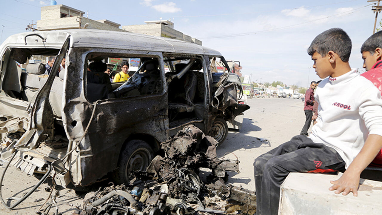MIDEAST-CRISIS/IRAQ Boys look at a destroyed car at the site of a car bomb attack in Habibia district in Baghdad, March 23, 2015. The bomb killed two people and wounded 15, police and medics said. REUTERS/Wissm al-Okili - RTR4UHTV