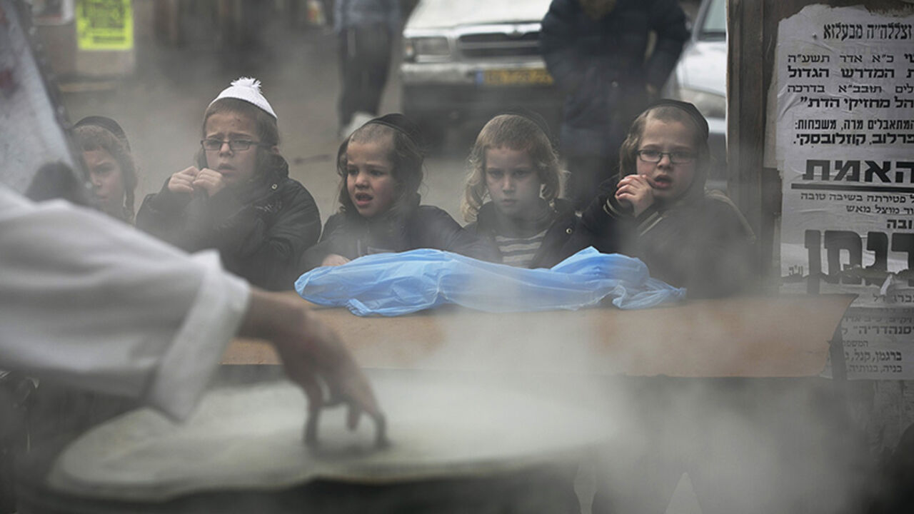 ISRAEL-RELIGION/ Ultra-Orthodox Jewish youths watch as a man dips cooking utensils in boiling water to remove remains of leaven in preparation for the Jewish holiday of Passover, in Jerusalem's Mea Shearim neighbourhood April 1, 2015. Passover, which starts on Friday, commemorates the flight of Jews from ancient Egypt, as described in the Exodus chapter of the Bible. According to the account, the Jews did not have time to prepare leavened bread before fleeing to the promised land. REUTERS/Baz Ratner - RTR4VREJ