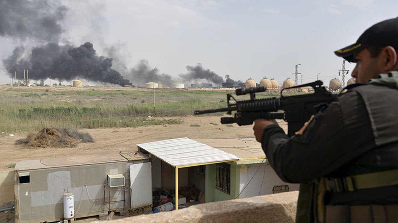 MIDEAST-CRISIS/ A member from the Iraqi security forces guards as smoke rises from Baiji oil refinery, north of Baghdad, Iraq May 26, 2015. Iraq's Shi'ite paramilitaries said on Tuesday they had taken charge of the campaign to drive Islamic State from the western province of Anbar, giving the operation an openly sectarian codename that could infuriate its Sunni Muslim population. Picture taken May 26, 2015. REUTERS/Stringer - RTX1EOY1