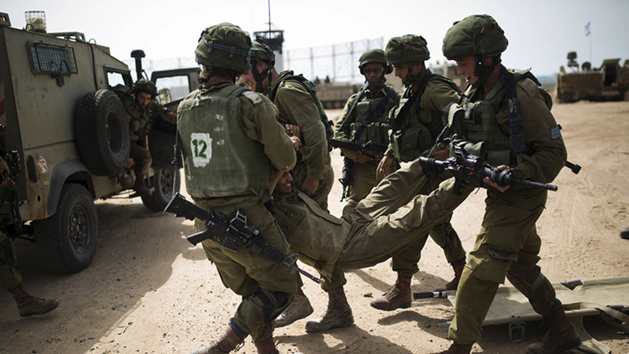 ISRAEL-PALESTINIANS/ Israeli soldiers carry their comrade during a military exercise in the region bordering the Gaza Strip, southern Israel June 7, 2015. REUTERS/Amir Cohen - RTX1FI8P