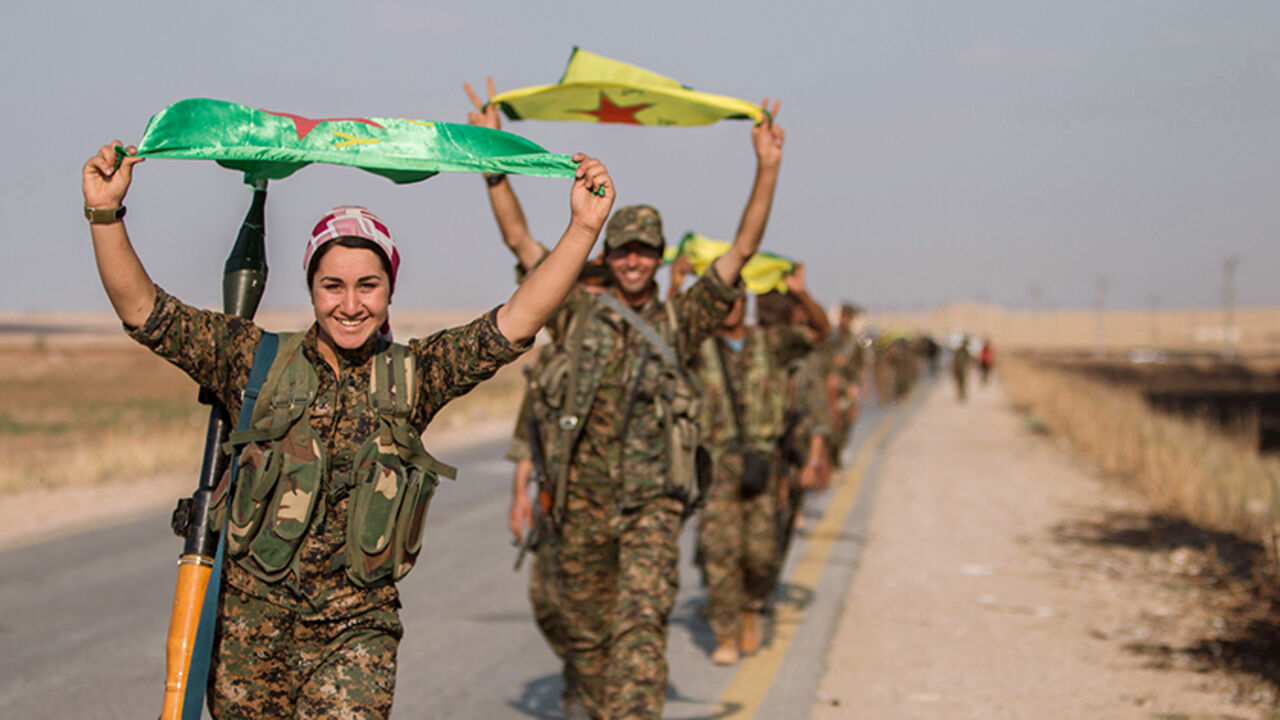 MIDEAST-CRISIS/KURDS Kurdish fighters gesture while carrying their parties' flags in Tel Abyad of Raqqa governorate after they said they took control of the area June 15, 2015. Syrian Kurdish-led forces said they had captured a town at the Turkish border from Islamic State on Monday, driving it away from the frontier in an advance backed by U.S.-led air strikes that has thrust deep into the jihadists' Syria stronghold. The capture of Tel Abyad by the Kurdish YPG and smaller Syrian rebel groups means the Syrian Kurds effectively