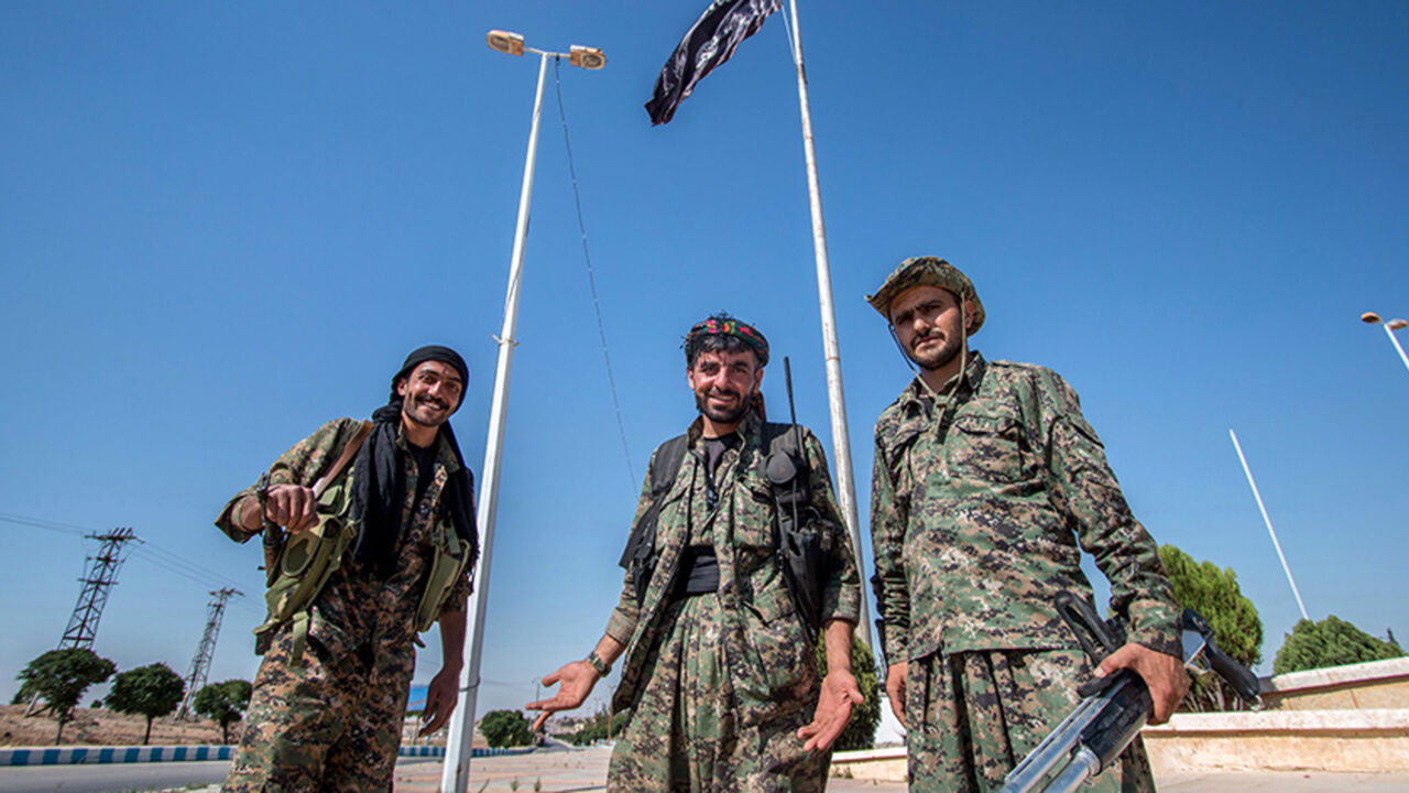 MIDEAST-CRISIS/SYRIA-KURDS Kurdish People's Protection Units (YPG) fighters stand near an Islamic State flag in Tel Abyad town, Raqqa governorate, June 16, 2015. With a string of victories over Islamic State, Syria's Kurds are proving themselves an ever more dependable ally in the U.S.-led fight against the jihadists and building influence that will make them a force in Middle Eastern politics. Aided by U.S.-led air strikes, the Kurdish-led YPG militia may have dealt Islamic State its worst defeat to date in Syria by seizing the town