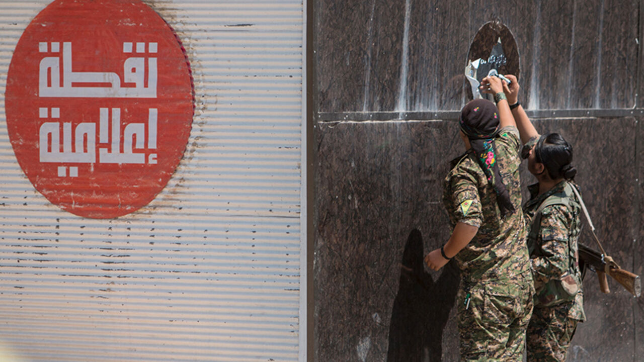 MIDEAST-CRISIS/SYRIA-KURDS Kurdish People's Protection Units (YPG) fighters remove an Islamic State sticker in Tel Abyad town, Raqqa governorate, June 16, 2015. With a string of victories over Islamic State, Syria's Kurds are proving themselves an ever more dependable ally in the U.S.-led fight against the jihadists and building influence that will make them a force in Middle Eastern politics. Aided by U.S.-led air strikes, the Kurdish-led YPG militia may have dealt Islamic State its worst defeat to date in Syria by seizing the town