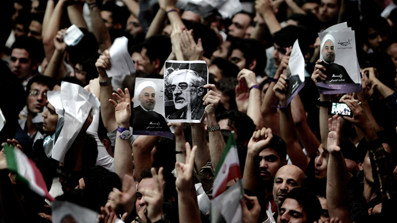 Nic6223688 A supporter of Iranian former Vice-President Mohammad Reza Aref, holds a portrait of opposition leader Mir Hossein Mousavi who is under the house arrest since February 2011, during a campaign rally for Aref in Tehran on June 10, 2013. AFP PHOTO/BEHROUZ MEHRI (Photo credit should read BEHROUZ MEHRI/AFP/Getty Images)