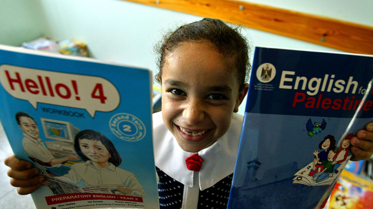 2452353AK002_school GAZA CITY, GAZA STRIP - SEPTEMBER 1: A Palestinian girl holds her new books after receiving them from the Dar Al-Arqam Islamic school on the first day of the new school year September 1, 2003 in Gaza City, Gaza Strip. About one million Palestinian students started the new school year in the Gaza Strip and the West Bank. (Photo by Abid Katib/Getty Images)