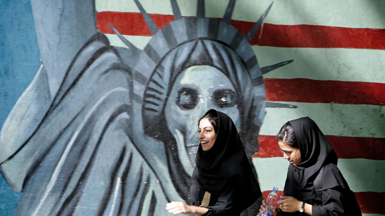 IRAN ISRAEL Iranian women walk past a satirical mural of the Statue of Liberty on the wall of former U.S. embassy in Tehran, Iran April 16, 2006. REUTERS/Morteza Nikoubazl - RTR1CJLR