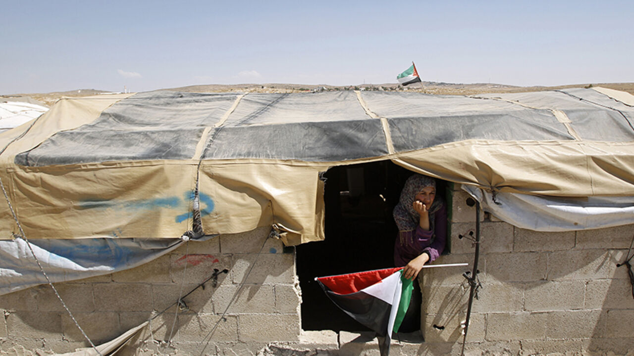 A Palestinian woman holds a Palestinian flag in the West Bank village of Susiya June 24, 2012. Susiya the Israeli settlement enjoys well-watered lawns, humming electricity, and the protection of a mighty state. One rocky hill away, Susiya the Palestinian village is parched and doomed. Picture taken June 24, 2012. To match Feature ISRAEL-PALESTINIANS/DEMOLITION   
REUTERS/Baz Ratner (WEST BANK - Tags: POLITICS TPX IMAGES OF THE DAY) - RTR347HZ