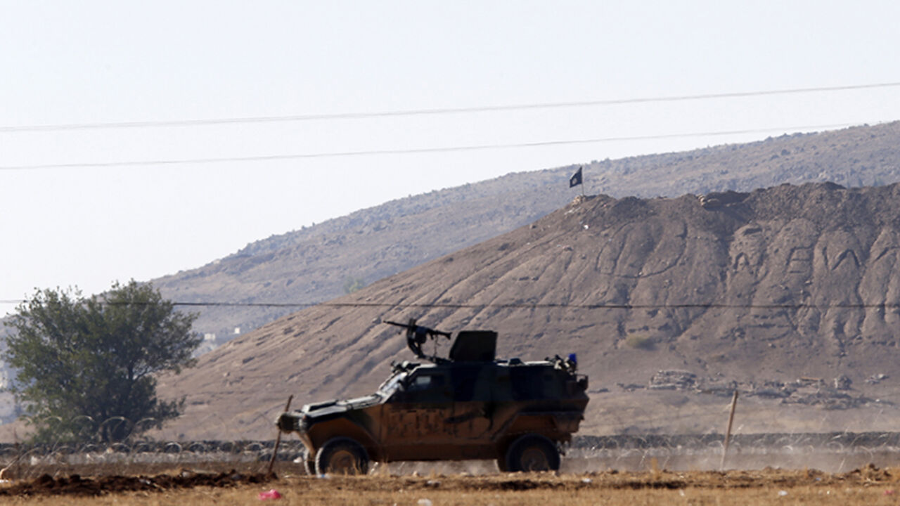 MIDEAST-CRISIS/ A black flag belonging to Islamic State is seen near the Syrian town of Kobani as a Turkish army vehicle takes up position on the Turkish-Syrian border near the southeastern town of Suruc in Sanliurfa province October 7, 2014. Islamic State fighters advanced into the south west of the Syrian Kurdish town of Kobani overnight, a monitoring group said on Tuesday, taking several buildings to gain attacking positions from two sides of the city. REUTERS/Umit Bektas (TURKEY - Tags: CIVIL UNREST MILITARY CONFLICT