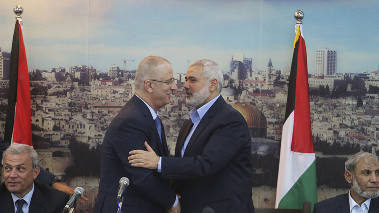 PALESTINIANS-GAZA-GOVERNMENT Senior Hamas leader Ismail Haniyeh (R) shakes hands with Palestinian Prime Minister Rami Hamdallah at Haniyeh's house in Gaza City October 9, 2014. Hamdallah arrived in the Hamas-dominated Gaza Strip on Thursday and convened the first meeting of a unity government there since a brief civil war in 2007 between Hamas and forces loyal to the Fatah party. REUTERS/Ibraheem Abu Mustafa (GAZA - Tags: POLITICS CIVIL UNREST) - RTR49J7M