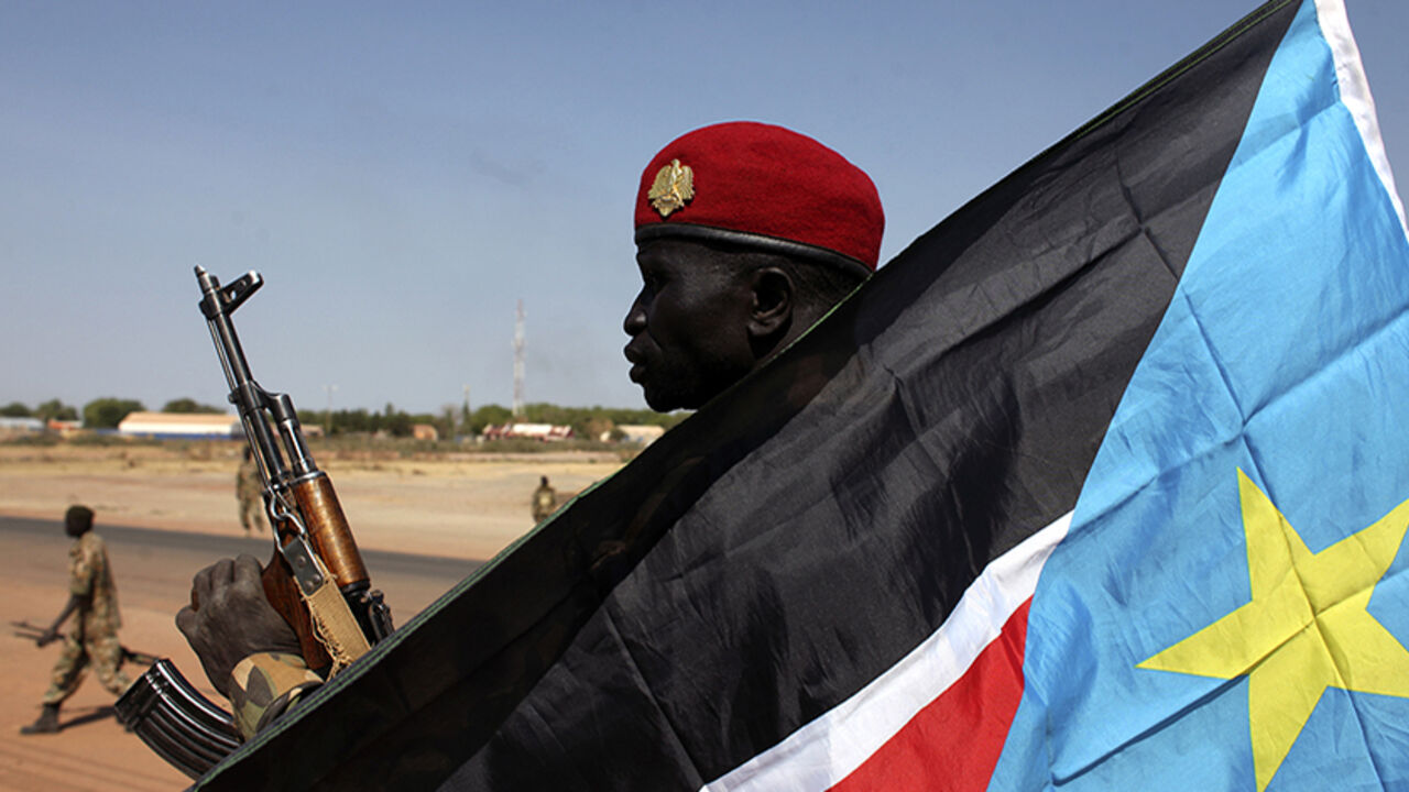 SOUTH-SUDAN/UNREST An SPLA soldier is pictured behind a South Sudan flag as he sits on the back of a pick-up truck in Bentiu, Unity state January 12, 2014. South Sudan's army said on Friday it had regained the rebel-held town of Bentiu, restoring government control of Unity state where oil production had been halted by fighting. The rebels said they made a "tactical withdrawal" from Bentiu to avoid civilian casualties. REUTERS/Andreea Campeanu (SOUTH SUDAN - Tags: CIVIL UNREST POLITICS CONFLICT) - RTX17AO2