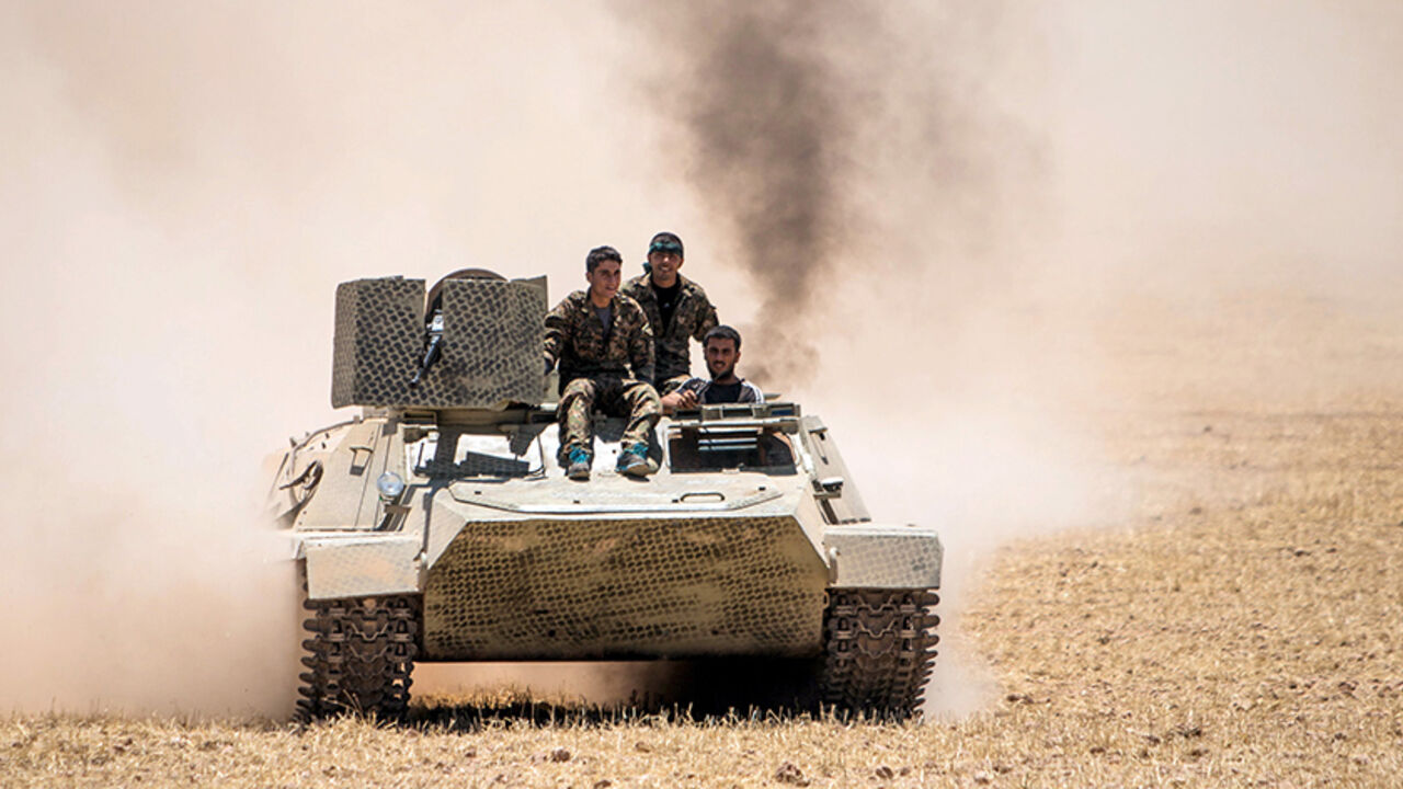 MIDEAST-CRISIS/SYRIA Kurdish People's Protection Units (YPG) fighters drive a tank at the eastern entrances to the town of Tal Abyad in the northern countryside of Raqqa, Syria, June 14, 2015, after they took control of nearby Suluk town from Islamic State fighters. The YPG, working with the U.S.-led alliance and small Syrian rebel groups, has pushed into Islamic State's Syrian stronghold of Raqqa province, threatening one of its supply lines to the jihadists' de facto capital, Raqqa city. REUTERS/Rodi Said - RTX1GFQ8