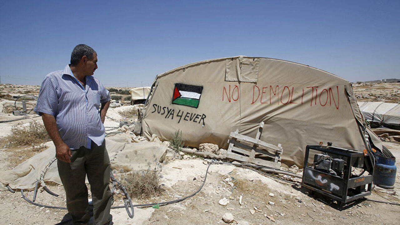 PALESTINIANS-ISRAEL/SUSYA Palestinian man Jihad Nuwaja stands next to a tent in Susiya village, south of the West Bank city of Hebron July 20, 2015. Sitting under a fig tree to escape the searing sun, Nuwaja looks out on the only land he knows - the dry expanse of the Hebron hills in the southern West Bank. Within days, his home is set to be demolished and he, his wife and 10 children expelled. REUTERS/Mussa Qawasma TPX IMAGES OF THE DAY - RTX1L1EB