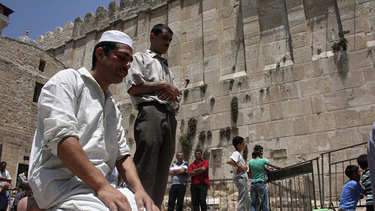 PALESTINIANS-ISRAEL/ Muslim men pray near the al-Ibrahimi mosque, also known as the Tomb of the Patriarchs, in the West Bank city of Hebron during the first Friday of the holy month of Ramadan August 5, 2011. REUTERS/Mussa Qawasma (WEST BANK - Tags: RELIGION) - RTR2PMYE