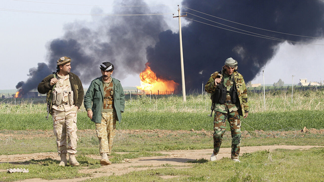 MIDEAST-CRISIS/IRAQ-OIL Smoke rises from the Khabbaz oilfield, behind Kurdish peshmerga forces, on the outskirts of Kirkuk, February 2, 2015. Production at the oilfield near the northern Iraq city of Kirkuk remained suspended on Monday after incurring severe damage during a weekend attack by Islamic State insurgents, Iraq's oil minister said. REUTERS/Ako Rasheed (IRAQ - Tags - Tags: CIVIL UNREST CRIME LAW POLITICS ENERGY) - RTR4NWQ7
