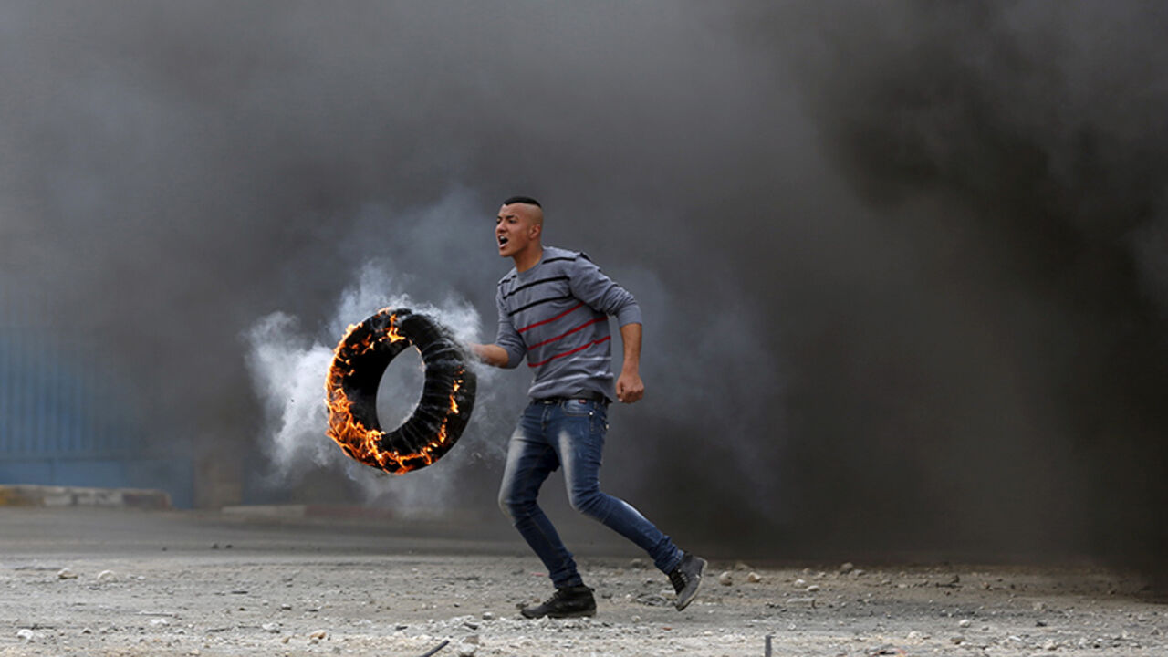 ISRAEL-PALESTINIANS/ A Palestinian protester moves a burning tyre during clashes with Israeli troops at a protest against Jewish settlements, in Jalazoun refugee camp near the West Bank city of Ramallah March 27, 2015. REUTERS/Mohamad Torokman TPX IMAGES OF THE DAY - RTR4V667