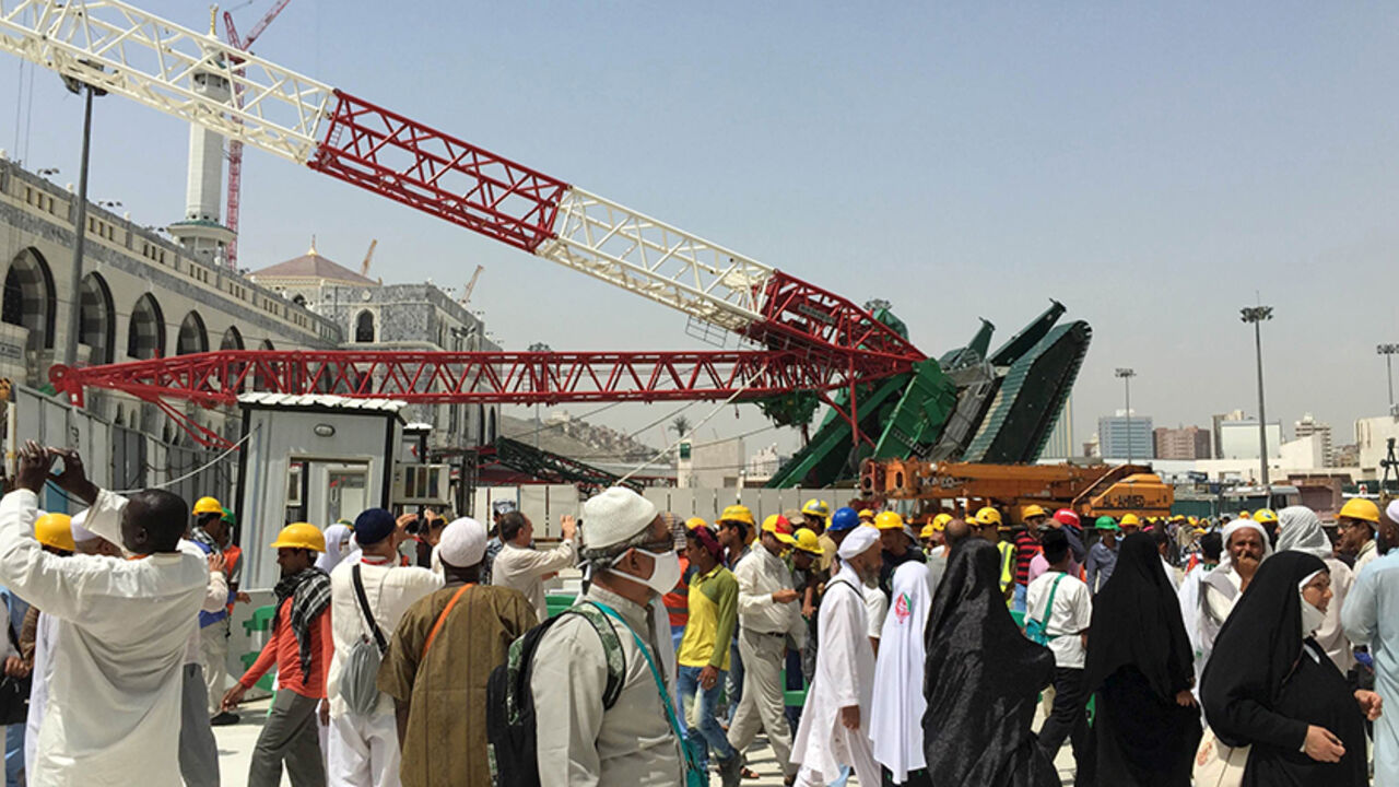 SAUDI-HAJ/ Muslim pilgrims walk near a construction crane which crashed in the Grand Mosque in the Muslim holy city of Mecca, Saudi Arabia September 12, 2015. At least 107 people were killed when the crane toppled over at Mecca's Grand Mosque on Friday, Saudi Arabia's Civil Defence authority said, less than two weeks before Islam's annual haj pilgrimage. REUTERS/Mohamed Al Hwaity - RTSR3D