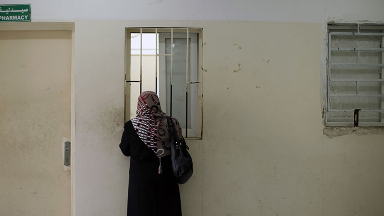 PALESTINIANS/ A Palestinian woman waits to receive medicine from a pharmacy at a hospital in Gaza City December 10, 2013. REUTERS/Suhaib Salem (GAZA - Tags: HEALTH) - RTX16CAD