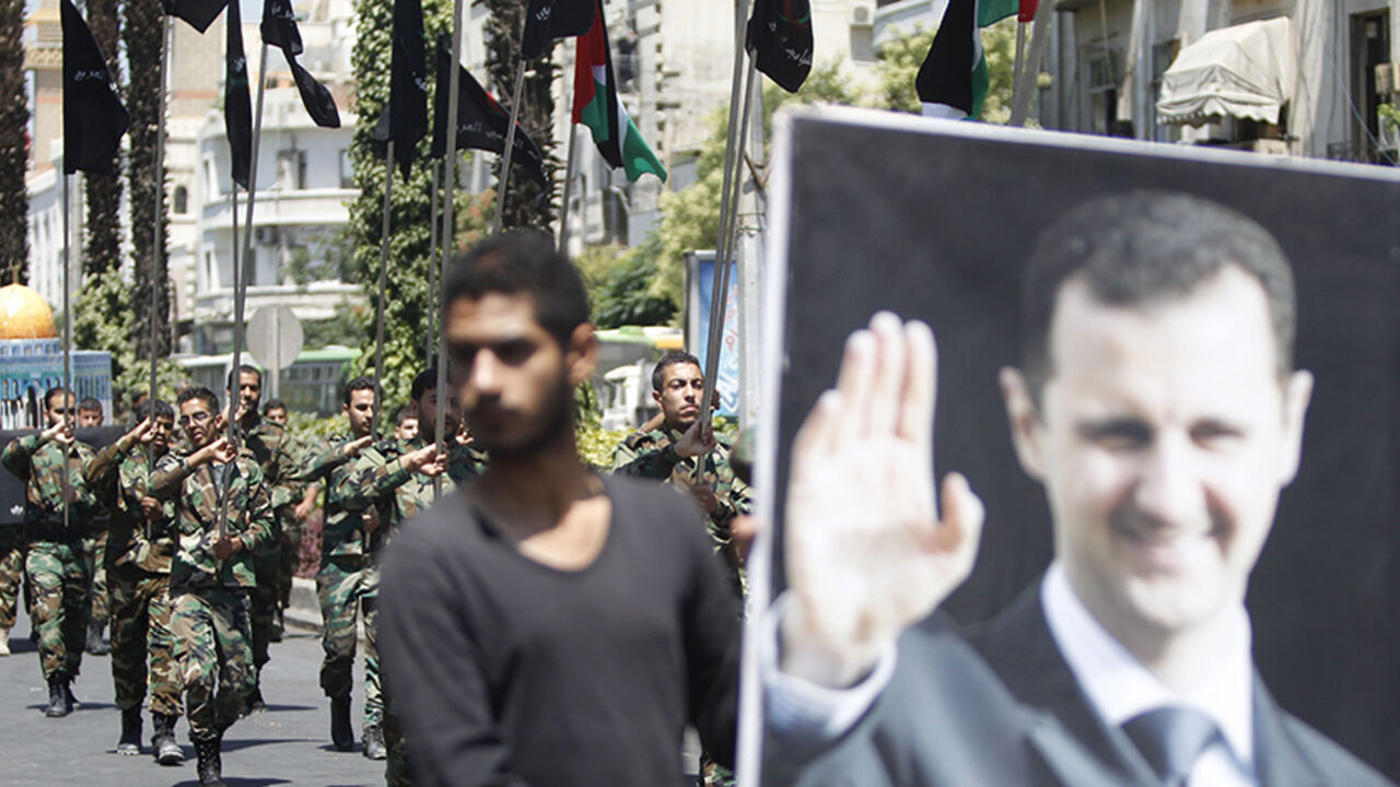 SYRIA-PALESTINIANS/ Palestinians living in Syria carry flags as one of them holds a picture depicting Syria's President Bashar al-Assad during a rally marking the annual al-Quds Day, or Jerusalem Day, on the last Friday of the Muslim holy month of Ramadan in Damascus, Syria July 10, 2015. REUTERS/Omar Sanadiki - RTX1JVFC