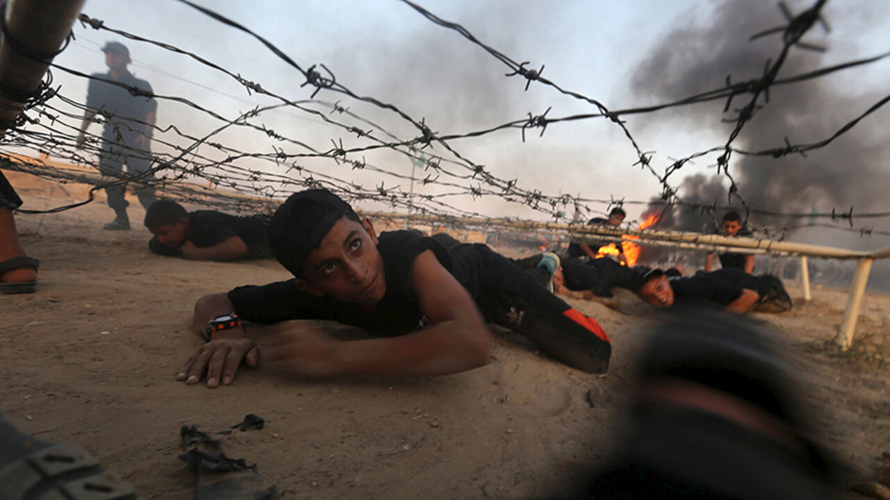 PALESTINIANS-MILITARY/ Young Palestinians crawl under an obstacle during a military-style exercise at Liberation Youths summer camp, organised by the Hamas movement, in Rafah in the southern Gaza Strip, August 1, 2015. Hamas stages dozens of military-style summer camps for young Palestinians in the Gaza Strip to prepare them to "confront any possible Israeli attack", organisers said. REUTERS/Ibraheem Abu Mustafa TPX IMAGES OF THE DAY - RTX1MOQN