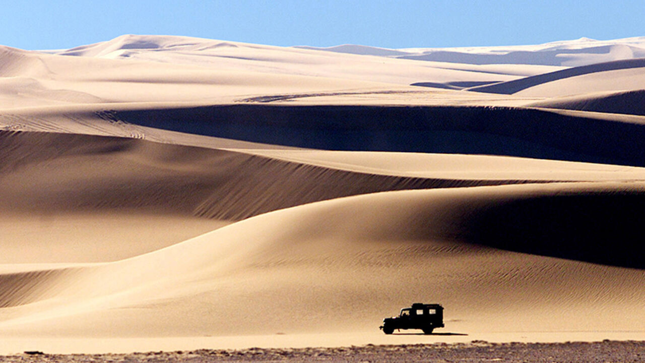 SIWA A four wheel drive vehicle crosses the sand dunes in the late afternoon sun near the Egyptian western desert oasis of Siwa. A four wheel drive vehicle crosses the sand dunes in the late afternoon sun near Egypt's western desert oasis of Siwa on February 3, 2002. HIGH RESOLUTION FILE BLIFE REUTERS/Aladin Abdel Naby REUTERS BOOKS ON THE ROAD BOOK - RTR13V9