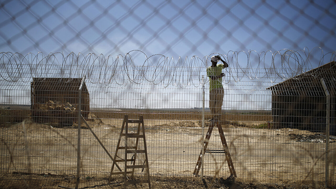 MIDEAST-GAZA/ISRAEL-BORDER An Israeli worker repairs a fence damaged by a tank in Kibbutz Nahal Oz , just outside the northern Gaza Strip, September 3, 2014. Israelis living on the Gaza border have warily returned home after fleeing constant mortar and rocket fire during a seven-week war, feeling it is just a matter of time before their villages are targeted again. Picture taken September 3, 2014. REUTERS/Amir Cohen (ISRAEL - Tags: POLITICS TPX IMAGES OF THE DAY CONFLICT) - RTR44YGI