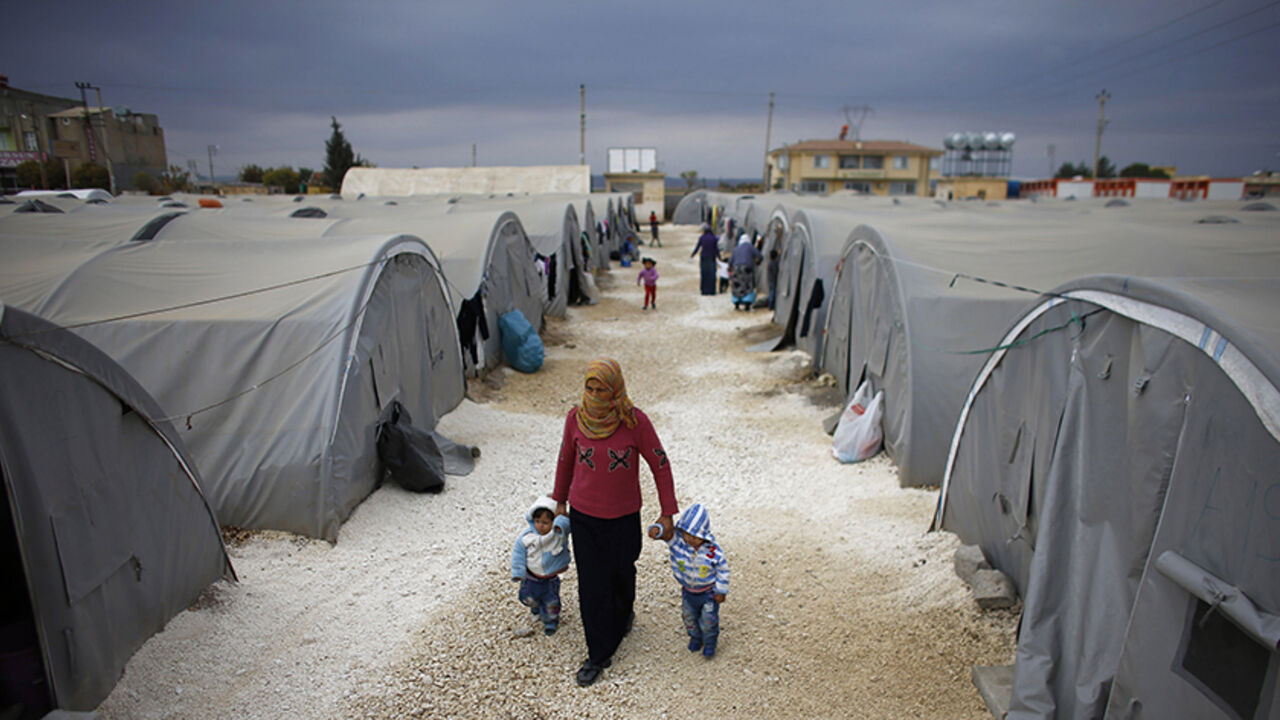 MIDEAST-CRISIS/ A Kurdish refugee woman from the Syrian town of Kobani walks with her children at a refugee camp in the border town of Suruc, Sanliurfa province November 17, 2014. REUTERS/Osman Orsal (TURKEY - Tags: POLITICS CONFLICT) - RTR4EES6