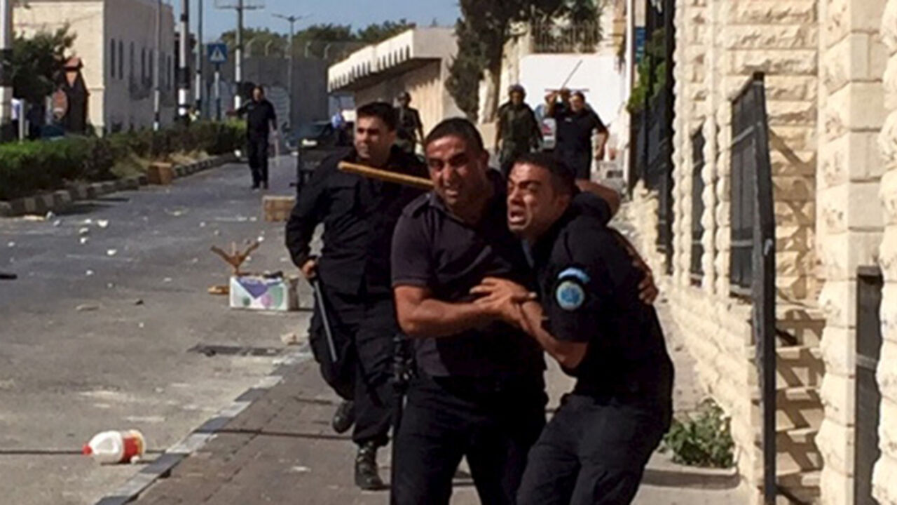 ISRAEL-PALESTINIANS-JERUSALEM A Palestinian policeman reacts next to fellow police officers as he tries to prevent Palestinian demonstrators (not pictured) from reaching an Israeli checkpoint during a protest against the Israeli police raid on Jerusalem's al-Aqsa mosque on Tuesday, in the occupied West Bank city of Bethlehem September 18, 2015. Israel deployed hundreds of extra police around the Old City of Jerusalem on Friday after Palestinian leaders called for a 'day of rage' to protest at new Israeli security measures. REUTERS/Luke