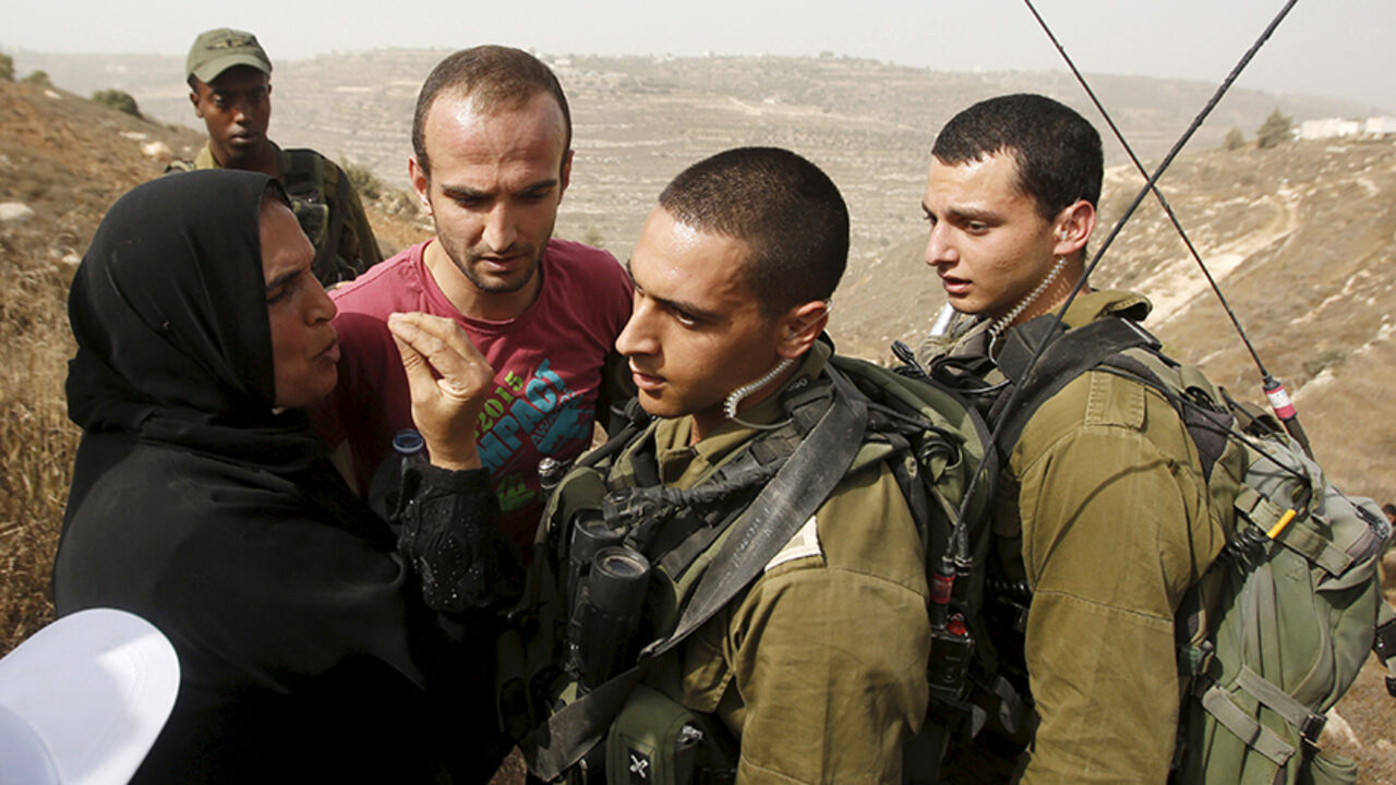 ISRAEL-PALESTINIANS/ A Palestinian woman argues with Israeli soldiers after Palestinian farmers said they were stopped by Israeli army and settlers from working in their farm land in Halhul town near Karme Tzur settlement, north of the occupied West Bank city of Hebron September 11, 2015. REUTERS/Mussa Qawasma - RTSL6J