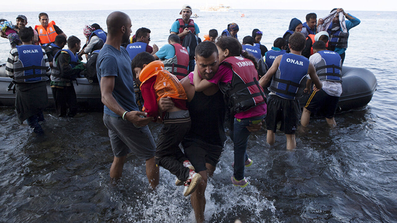 EUROPE-MIGRANTS/GREECE A Syrian refugee carries two children moments after arriving on a dinghy on the Greek island of Lesbos, September 8, 2015. Greece asked the European Union for aid to prevent it being overwhelmed by refugees, as a minister said arrivals on Lesbos had swollen to three times as many as the island could handle. REUTERS/Dimitris Michalakis - RTX1RPL9