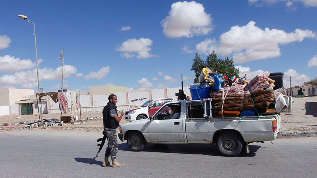 LIBYA/ Civilians returning to their homes with their belongings pass a checkpoint manned by police in the centre of Bani Walid, some 170km (106 miles) south of Tripoli, November 3, 2012. REUTERS/Ismail Zitouny (LIBYA - Tags: POLITICS CIVIL UNREST) - RTR39Y9U