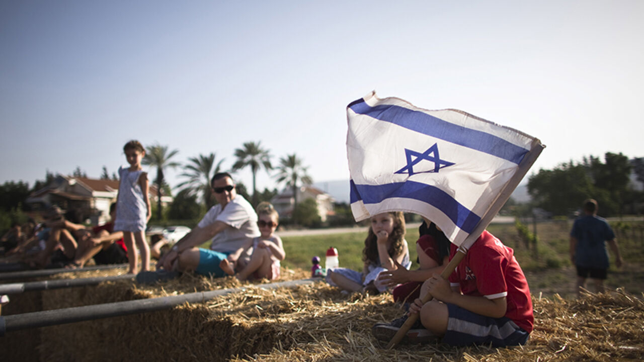 ISRAEL-KIBBUTZ/ Children sit on bales of hay at the annual harvest festival in Kibbutz Degania Alef on the shores of the Sea of Galilee, northern Israel May 23, 2015. Twenty-five years ago kibbutzim, collective communities traditionally based on agriculture, seemed all but doomed. But the last few years have seen a surprising turnaround, with young families seeking to escape the high cost of living and alienation they find in cities for a cheaper, rural lifestyle in a closely knit community. Picture taken May 23, 2015. REU