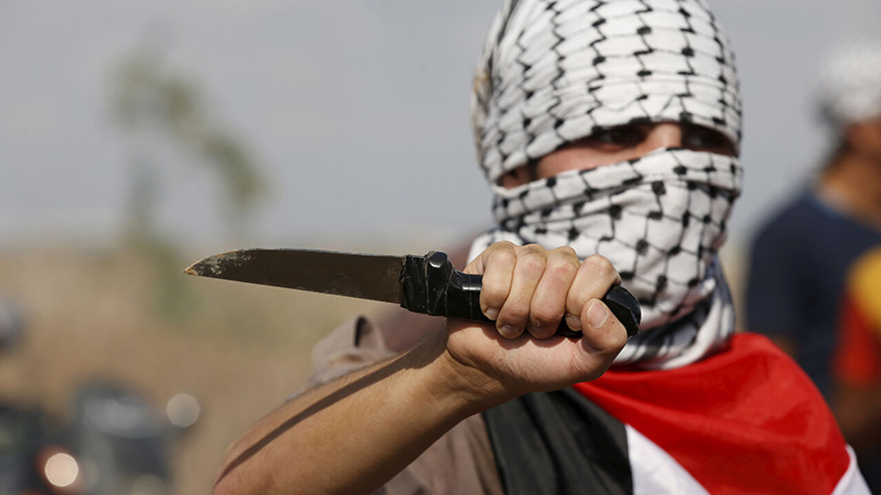 PALESTINIANS-ISRAEL/GAZA A masked Palestinian protester holds a knife during a protest near the Israeli border fence in northeast Gaza October 9, 2015. Israeli troops fired across the border into Gaza on Friday, killing four Palestinians and wounding at least a dozen others who were throwing stones during a rally in support of protests in Jerusalem, hospital officials in Gaza said. REUTERS/Mohammed Salem - RTS3QE4