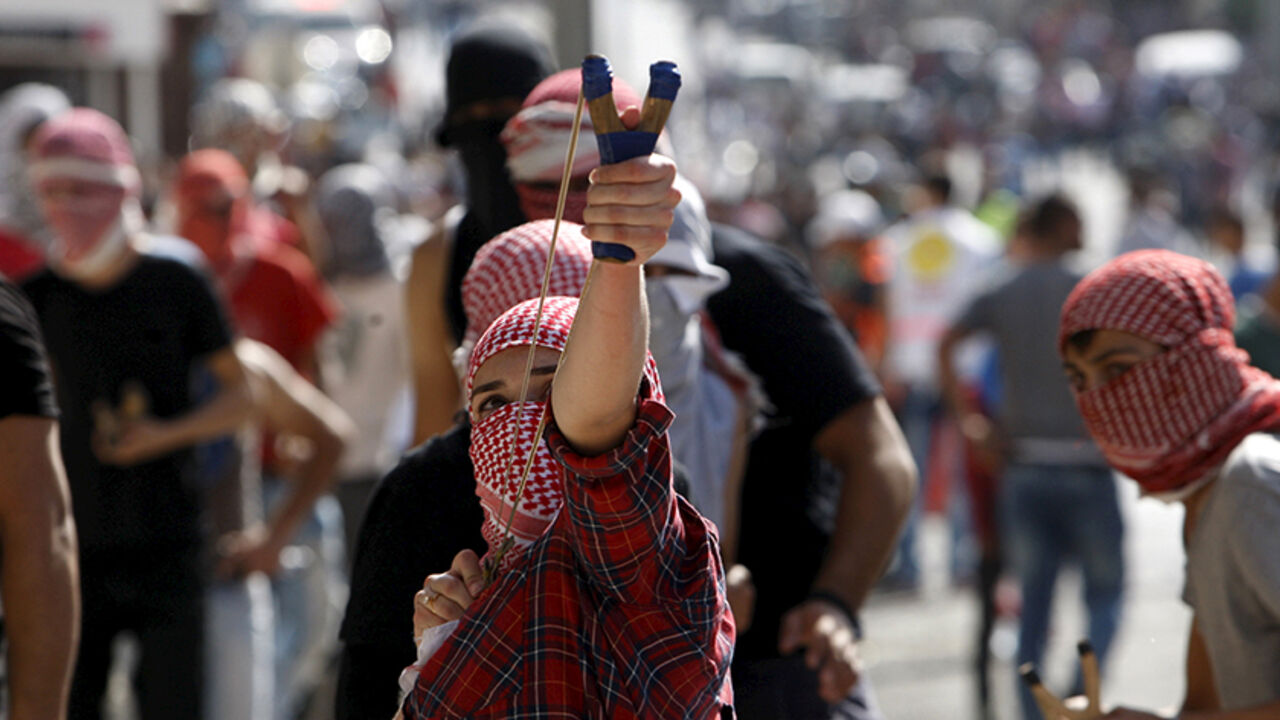 A Palestinian girl uses a slingshot to throw stones at Israeli troops during clashes in the West Bank city of Bethlehem October 14, 2015. Seven Israelis and 30 Palestinians, including children and assailants, have been killed in two weeks of bloodshed in Israel, Jerusalem and the occupied West Bank. The violence has been partly triggered by Palestinians' anger over what they see as increased Jewish encroachment on Jerusalem's Al-Aqsa mosque compound, also revered by Jews as the site of two destroyed Jewish 