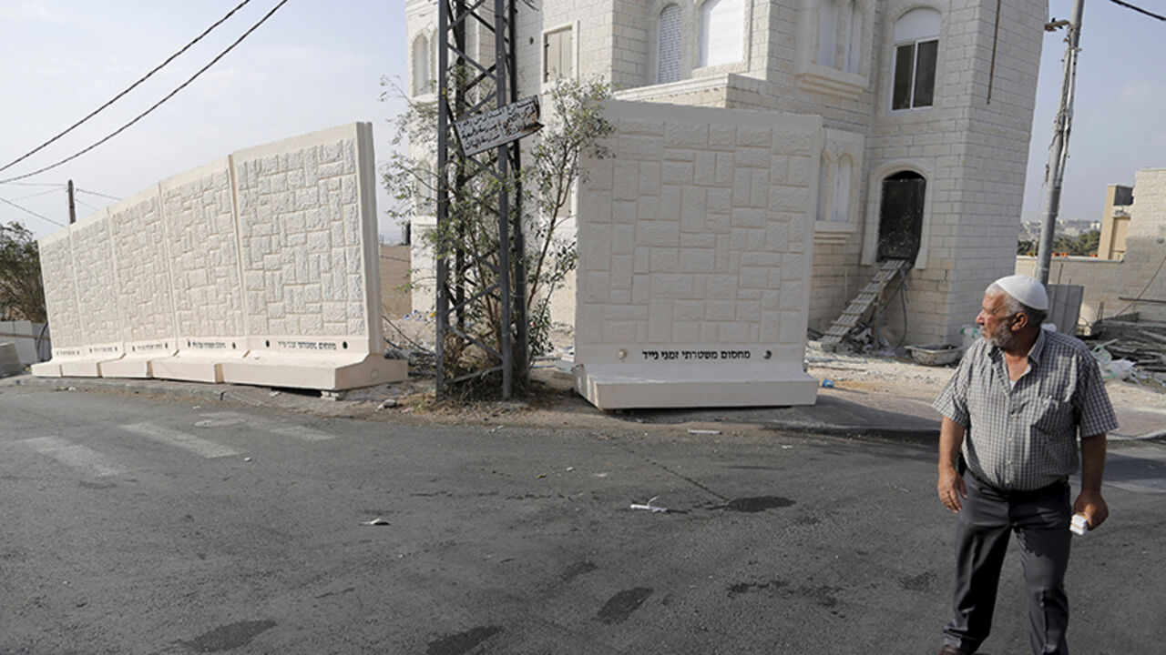 A Palestinian man walks past a newly erected temporary concrete wall that measures around 10 meters in length, in the East Jerusalem neighbourhood of Jabel Mukaber October 19, 2015. REUTERS/Ammar Awad   - RTS52AL