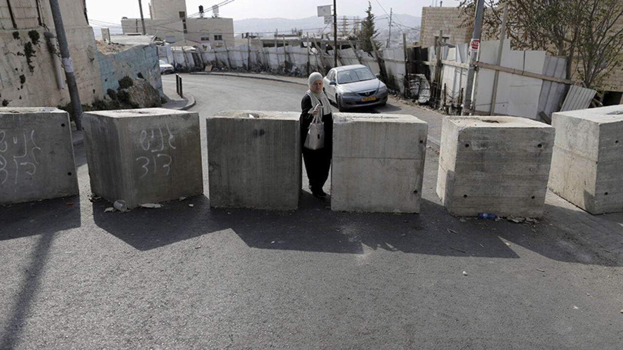ISRAEL-PALESTINIANS/ A woman passes through concrete blocks that were placed by Israeli police last week, in the East Jerusalem neighbourhood of Jabel Mukaber October 19, 2015. REUTERS/Ammar Awad - RTS52BK